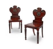 A pair of Regency mahogany carved armorial hall chairs