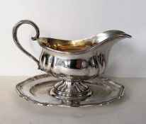 A German 800 silver sauceboat on an integrated oval tray with wavy rim decoration