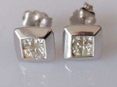 A pair of diamond stud earrings, each set with four princess-cut diamonds