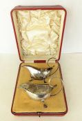 A cased Edwardian pair of silver sauce boats pie-crust rims on three shell and hoof feet,