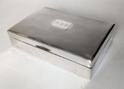 An Art Deco silver cigarette box of oblong form with engine turned decoration, filled cartouche