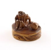 NETSUKE AFFE, Buchsbaum, auf eine Holzscheibe sitzend und neben sich einen Knüpfel der mit einem Se