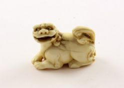 NETSUKE SHISHI, Elfenbein, der liegende Wächterlöwe hat einen beweglichen Ball im geöffneten Maul, 