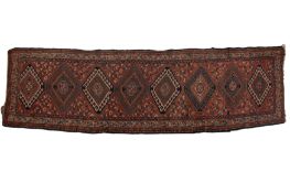 A Karaja runner, the brick red field with a row of six hooked lozenge medallions,