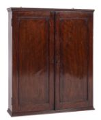A Regency mahogany wall cabinet, early 19th century; with reeded cornice above twin panel doors,