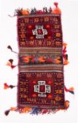 A Balouchistan saddle bag, the wine twin faces with cruciform hooked medallions, 109cm x 52cm,
