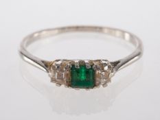 An emerald and diamond ring, the square cut emerald between two square cut diamonds,