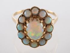 An opal ring, the central oval cabochon opal claw set within a surround of circular cabochon opals,