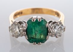 An 18ct gold, emerald-cut emerald and round, brilliant-cut diamond, three-stone ring,