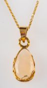 An opal pendant, the pear shaped cabochon opal in a scrolled setting, stamped 14k,