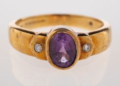 An amethyst and diamond ring, the oval cut amethyst collet set between two brilliant cut diamonds,