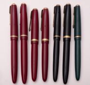 A group of seven Parker Duofold fountain pens, consisting of four maroon, two black and one green.