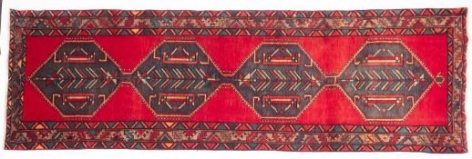 A Heriz runner, the red field with a row of four sea green hexagonal medallions,