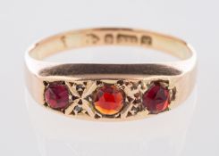 A 9ct yellow gold Edwardian ring, a 'gypsy' style setting with three circular-cut red stones,