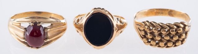 A group of three 9ct rings, a 9ct yellow gold ring set with an oval-cut red stone cabochon,