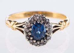 An antique cluster ring, set centrally with an oval-cut sapphire,