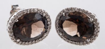A pair of cluster earrings, each set with an oval mixed-cut smokey quartz,