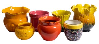 A collection of seven glazed pottery jardinieres in bright colours.