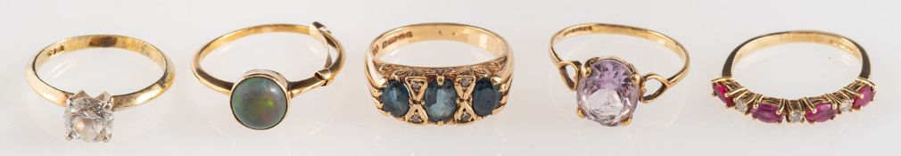 A group of five gem-set rings, including