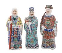 A set of three Chinese famille-rose figures of Immortals, each wearing brightly enamelled robes,