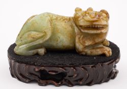 A Chinese jade figure of brown flecked celadon colour modelled as recumbent lion dog, 15cm long,