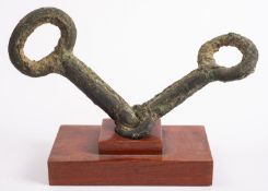 A Chinese bronze horse snaffle bit probably Tang Dynasty, 19cm hardwood stand.