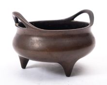 A small Chinese bronze tripod censer with loop handles and short tapering feet,