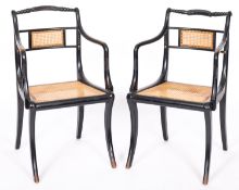 A pair of ebonised wood and canework elbow chairs in Regency style,