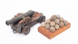 A small group of grape or musket shot on a later wooden base, together with small model cannon.