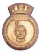 A ship's bronze badge for the Royal Navy vessel HMS 'Rangatira' mounted on a mahogany plinth,