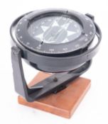 A 4 inch compass by Heath Marine, London, in a black case with mount on a wooden stand, 16cm high.
