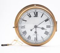A Smiths brass bulkhead clock, with white enamel dial and Roman numerals signed as per title, 23.