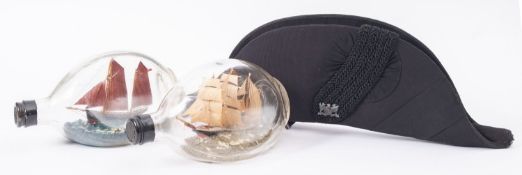 Two early 20th century model ships in bottles, 20cm long, together with a black bicorn hat,