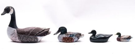 Three painted wooden decoy ducks and green glazed pottery duck.