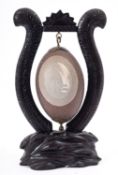 Australian Interest; a hand carved Emu egg, the hanging egg set on a wooden frame,