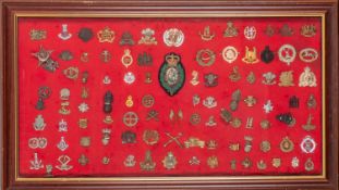 A framed and glazed group of military cap badges.