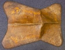 A brown leather elephant saddle together with an animal skin.