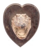 An early 20th century taxidermy alligator head, unsigned on a heart shaped plinth,