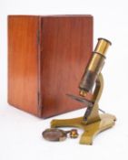 An early 20th century lacquered brass student microscope in a mahogany case, with spare objective,