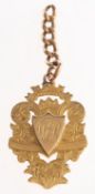 An 18ct yellow gold watch fob, ornately engraved with foliage and initials in a central crest,