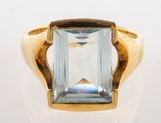A 9ct gold aquamarine dress ring, semi-rubover set with a rectangular step-cut aquamarine,