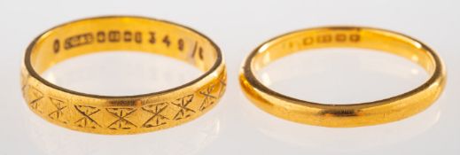 A group of two 22ct gold wedding bands, one with a faint engraved pattern, UK hallmark, approx.