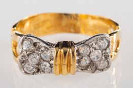 A 'bow' designed ring, of bi-colour and the bow set with circular-cut paste stones,