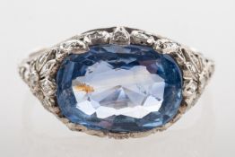 An Edwardian sapphire and diamond ring, claw set to the centre with a cushion-cut Ceylon sapphire,