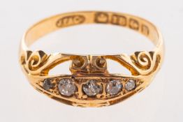 An Edwardian 18ct gold diamond ring, set with five old-cut diamonds in an openwork scroll setting,