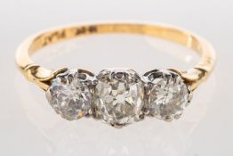 A three stone diamond ring, set with an old mine-cut diamond and two old-cut diamonds,