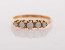 A five stone opal ring, claw set with five graduated circular-cut opal cabochons, marked 18c,