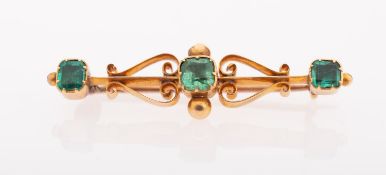 An antique emerald brooch, of ornate openwork design and set with three square-cut emeralds,