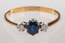 A 9ct gold sapphire and diamond ring, set with an oval-cut sapphire and two brilliant-cut diamonds,