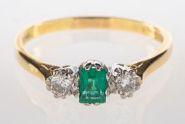 An 18ct gold three stone emerald and diamond ring, set to the centre with a rectangular-cut emerald,